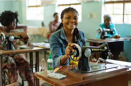 A sponsored student learning to sew through Child Impact